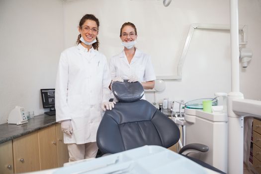 Dentist and assistant smiling at camera at the dental clinic