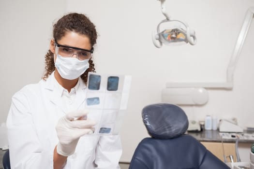 Dentist examining xrays wearing surgical mask at the dental clinic