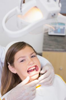 Dentist putting mouth retractor on little girl at the dental clinic