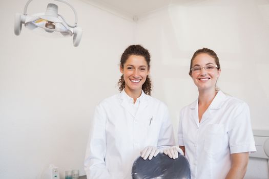 Dentist and assistant smiling at camera at the dental clinic