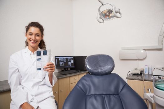 Dentist holding xrays smiling at camera at the dental clinic