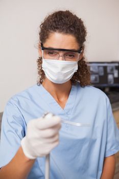 Dentist in mask and protective glasses holding drill at the dental clinic