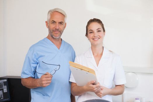 Dentist and assistant smiling at camera at the dental clinic