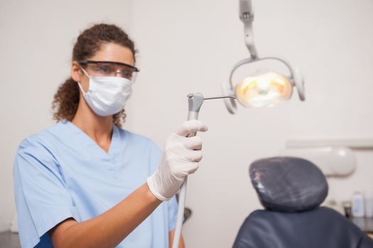 Dentist in mask and protective glasses holding drill at the dental clinic