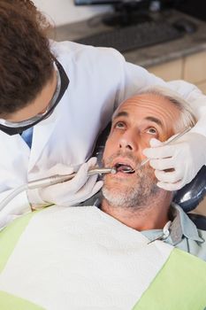 Dentist examining a patients teeth in the dentists chair at the dental clinic