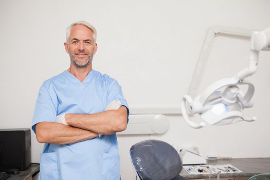 Dentist in blue scrubs smiling at camera at the dental clinic