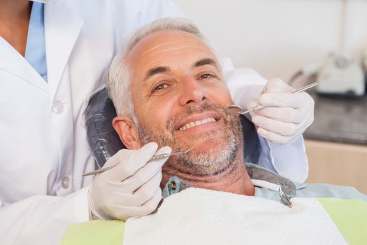 Dentist examining a patients teeth in the dentists chair at the dental clinic