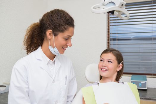Pediatric dentist smiling with little girl in the chair at the dental clinic