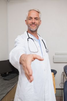 Dentist offering hand to camera at the dental clinic