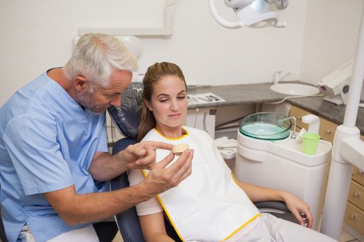 Dentist showing patient model of teeth at the dental clinic