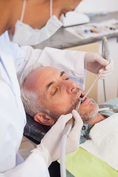 Dentist examining a patients teeth in the dentists chair at the dental clinic