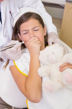 Pediatric dentist trying to see coughing patients teeth at the dental clinic