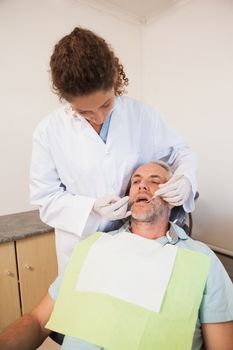 Dentist examining a patients teeth in the dentists chair at the dental clinic