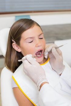 Pediatric dentist examining a little girls teeth in the dentists chair at the dental clinic