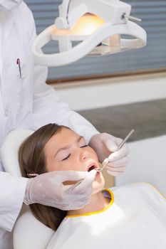 Pediatric dentist examining a patients teeth in the dentists chair at the dental clinic