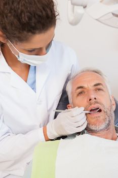 Dentist examining a patients teeth in the dentists chair at the dental clinic