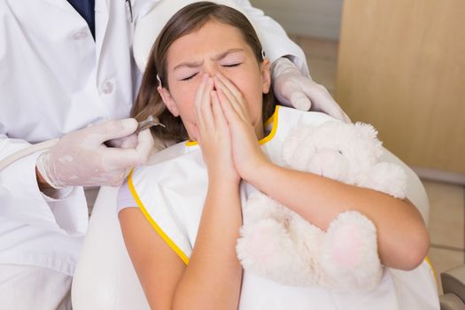 Pediatric dentist trying to see sneezing patients teeth at the dental clinic