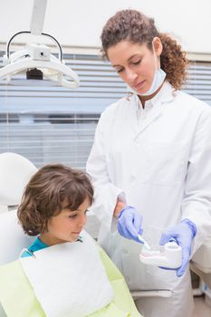 Pediatric dentist showing little boy teeth model at the dental clinic