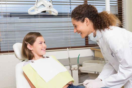 Pediatric dentist examining little girls teeth in the dentists chair at the dental clinic
