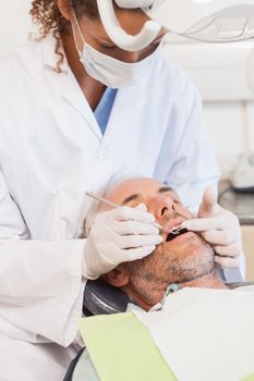 Dentist examining a patients teeth in the dentists chair at the dental clinic