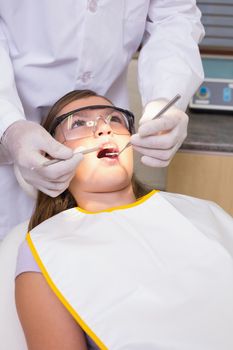 Pediatric dentist examining a patients teeth in the dentists chair at the dental clinic