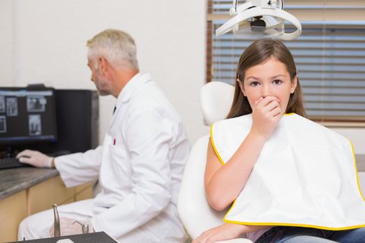 Terrified little girl looking at camera in dentists chair at the dental clinic