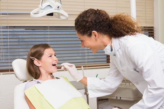 Pediatric dentist examining little girls teeth in the dentists chair at the dental clinic