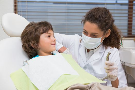 Pediatric dentist showing little boy in chair the drill at the dental clinic