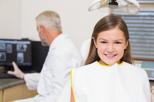 Smiling little girl looking at camera in dentists chair at the dental clinic