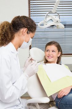 Pediatric dentist speaking with little girl in the dentists chair at the dental clinic