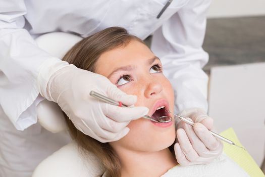 Pediatric dentist examining a patients teeth in the dentists chair at the dental clinic