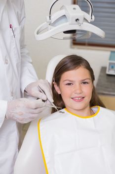 Little girl sitting in dentists chair smiling at camera at the dental clinic