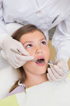 Pediatric dentist examining a patients teeth in the dentists chair at the dental clinic