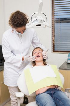 Pediatric dentist examining a patients teeth in the dentists chair at the dental clinic