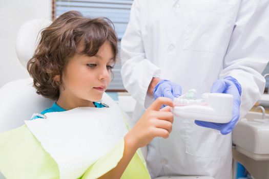 Pediatric dentist showing little boy teeth model at the dental clinic
