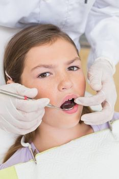 Pediatric dentist examining a patients teeth in the dentists chair at the dental clinic