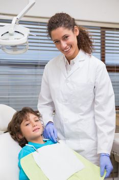 Pediatric dentist smiling with little boy in the chair at the dental clinic