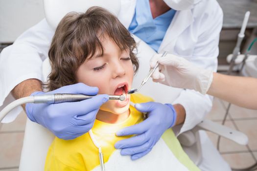 Pediatric dentist examining a little boys teeth in the dentists chair at the dental clinic