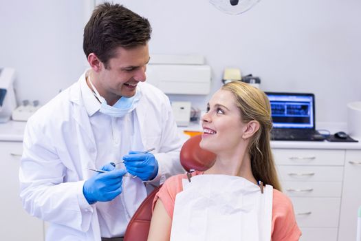 Dentist interacting with female patient while examining in clinic