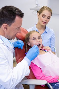 Dentist examining with young patient at dental clinic