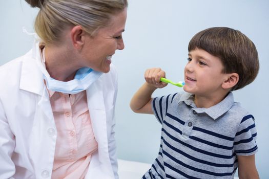 Boy holding toothbrush while looking at dentist at clinic