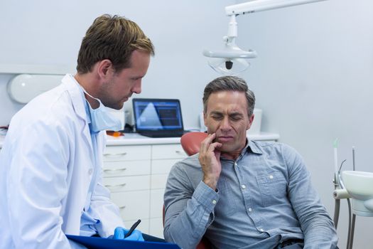 Dentist examining a male patient in dental clinic