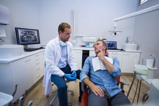 Dentist talking to male patient in dental clinic