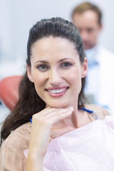 Portrait of smiling female patient sitting on dentist chair at dental clinic