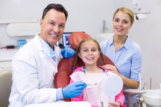 Portrait of dentist with young patient and his mother at dental clinic