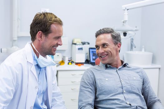 Smiling dentist and patient interacting with each other in dental clinic