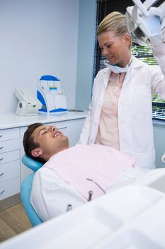 Smiling man lying on dentist chair while doctor standing at clinic