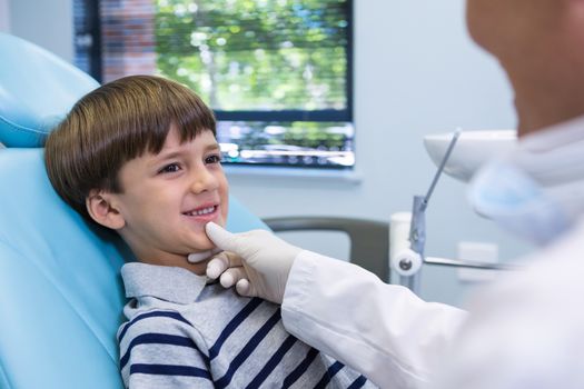 Smiling boy looking at dentist while sitting on chair in medical clinic