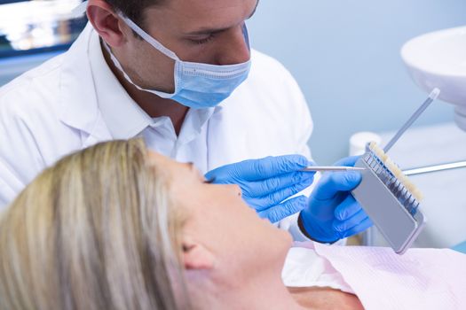 High angle view of dentist showing equipment to patient at medical clinic