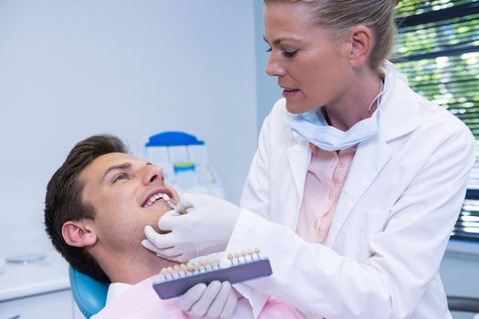 Dentist holding equipment while examining patient at medical clinic